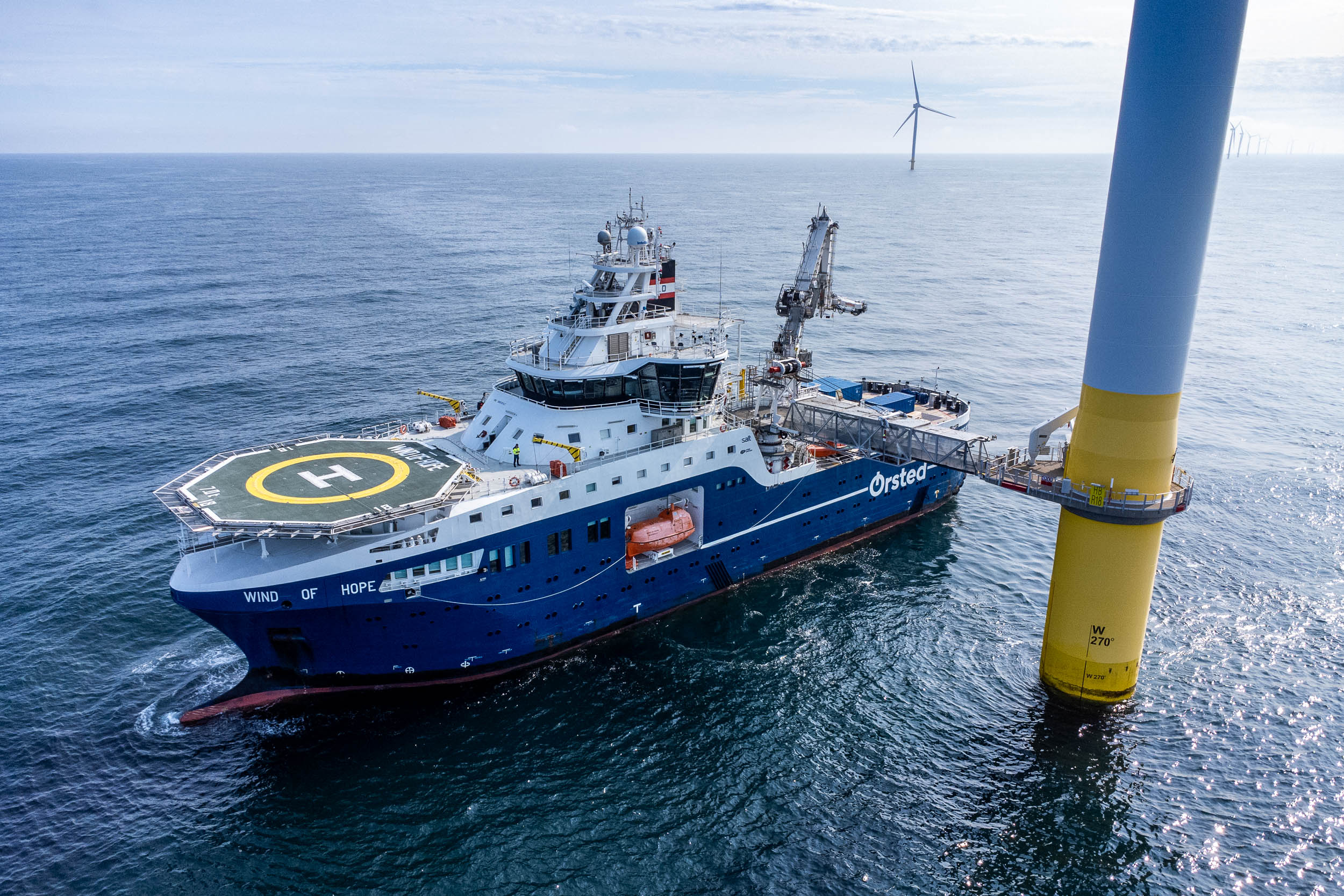 Un navire et sa passerelle gyro-stabilisée s'apprête à transférer des techniciens sur une éolienne en mer.