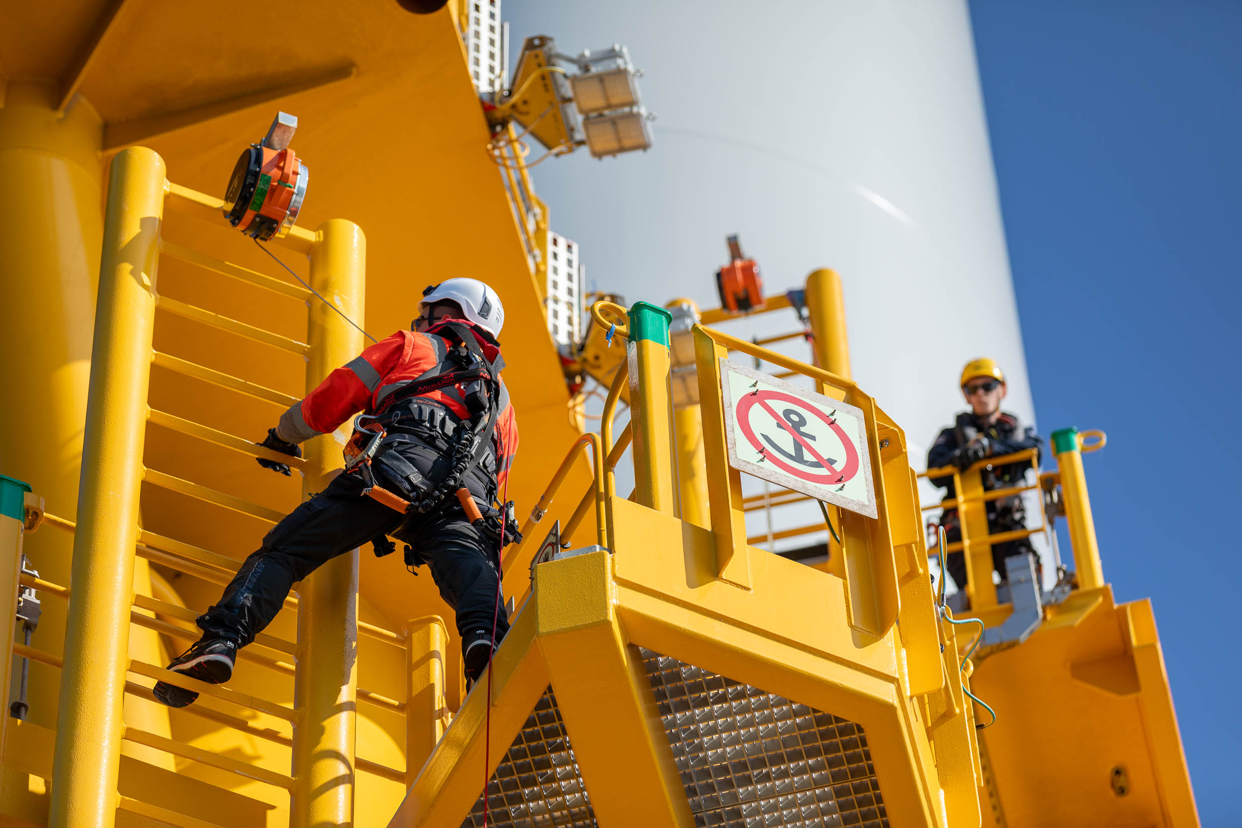 Un technicien grimpe sur une éolienne en mer au large de la côte Bretonne.